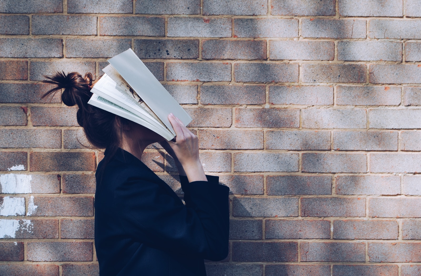 Foto van Siora Photography woman covering her face with white book
